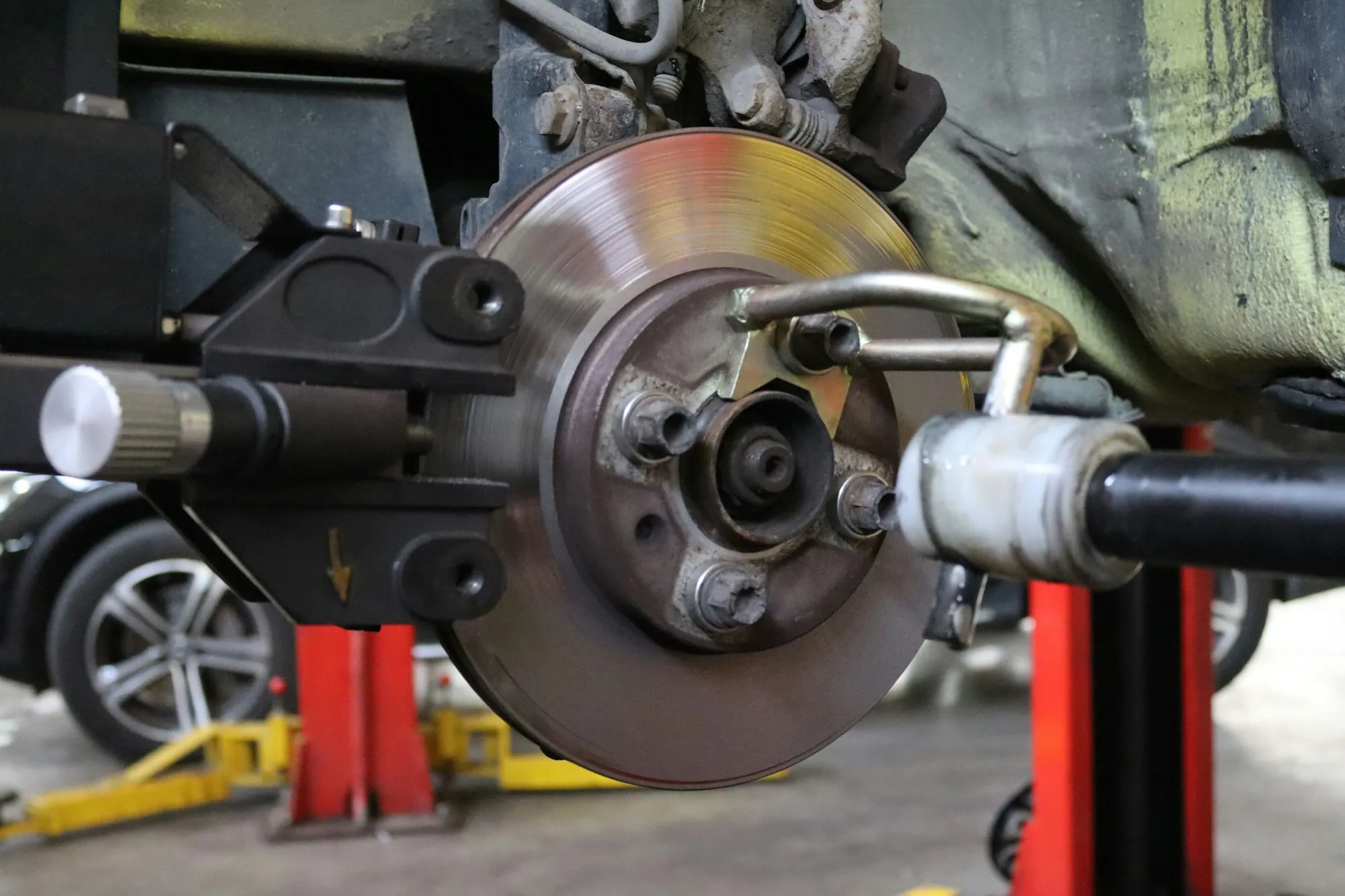 Brake caliper and drilled rotor on a car raised in the shop